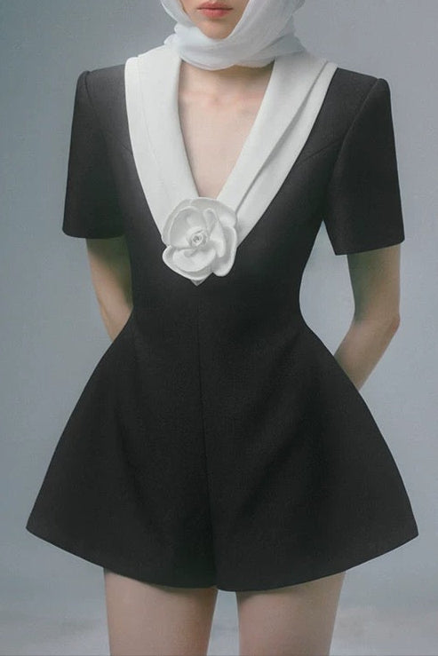 Person wearing a black outfit with white accents and a white hat on a gray background