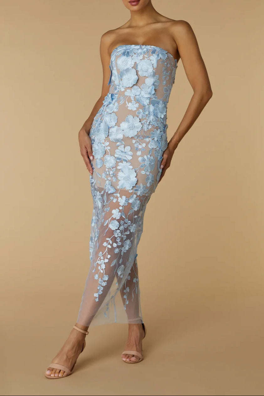 Woman wearing a light blue floral strapless gown on a beige background